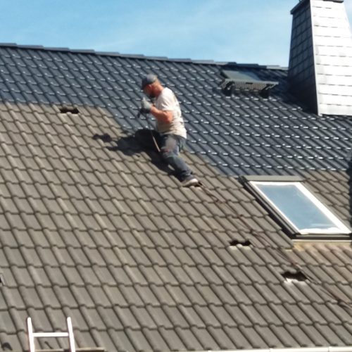 Mitarbeitender trägt neue Beschichtung auf Dach auf
